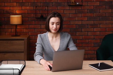 Photo of Woman working with laptop at desk in home office