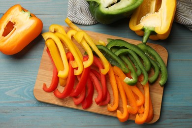 Photo of Cut colorful bell peppers on blue wooden table, flat lay