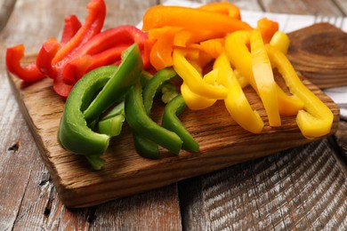 Photo of Cut colorful bell peppers on wooden table, closeup