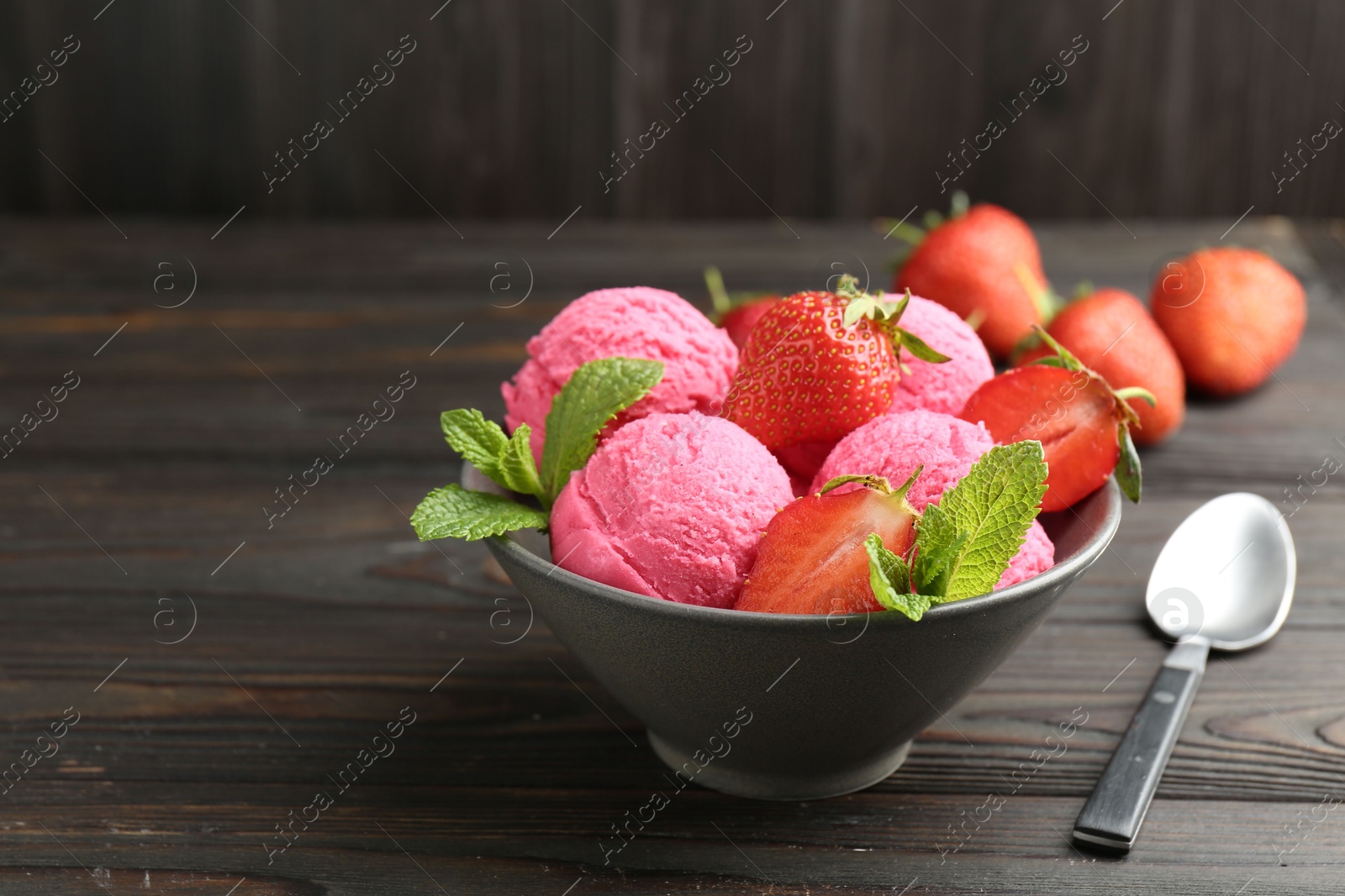 Photo of Tasty sorbet with strawberries and mint served on wooden table, closeup. Space for text