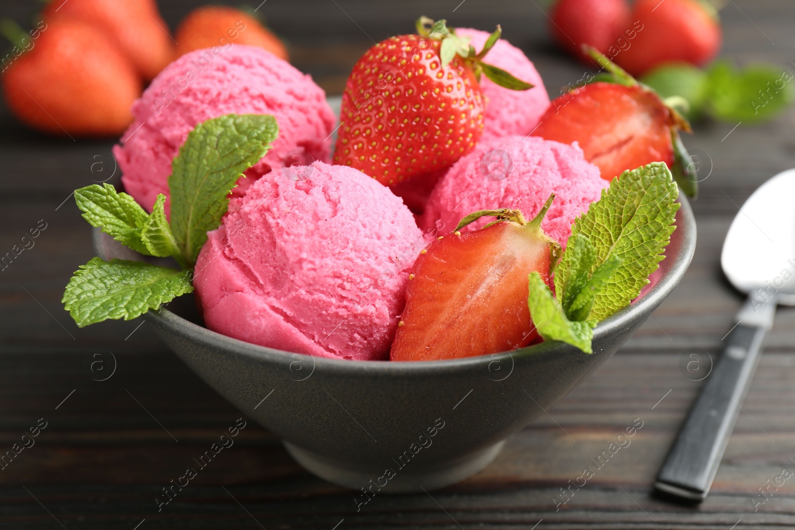 Photo of Tasty sorbet with strawberries and mint served on wooden table, closeup