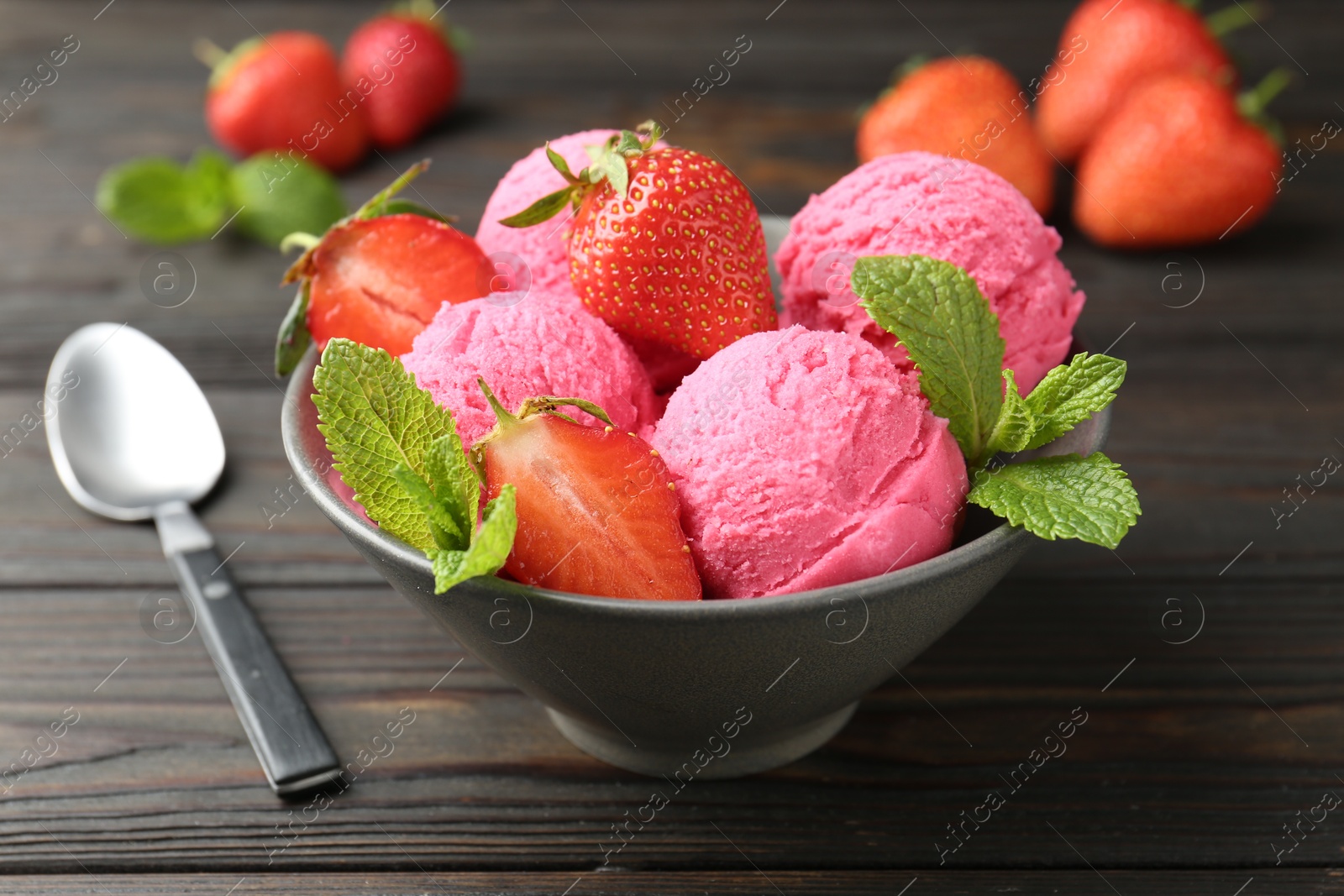 Photo of Tasty sorbet with strawberries and mint served on wooden table, closeup
