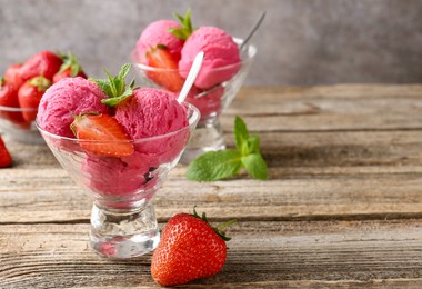 Photo of Tasty sorbet with strawberries and mint served on wooden table, closeup. Space for text