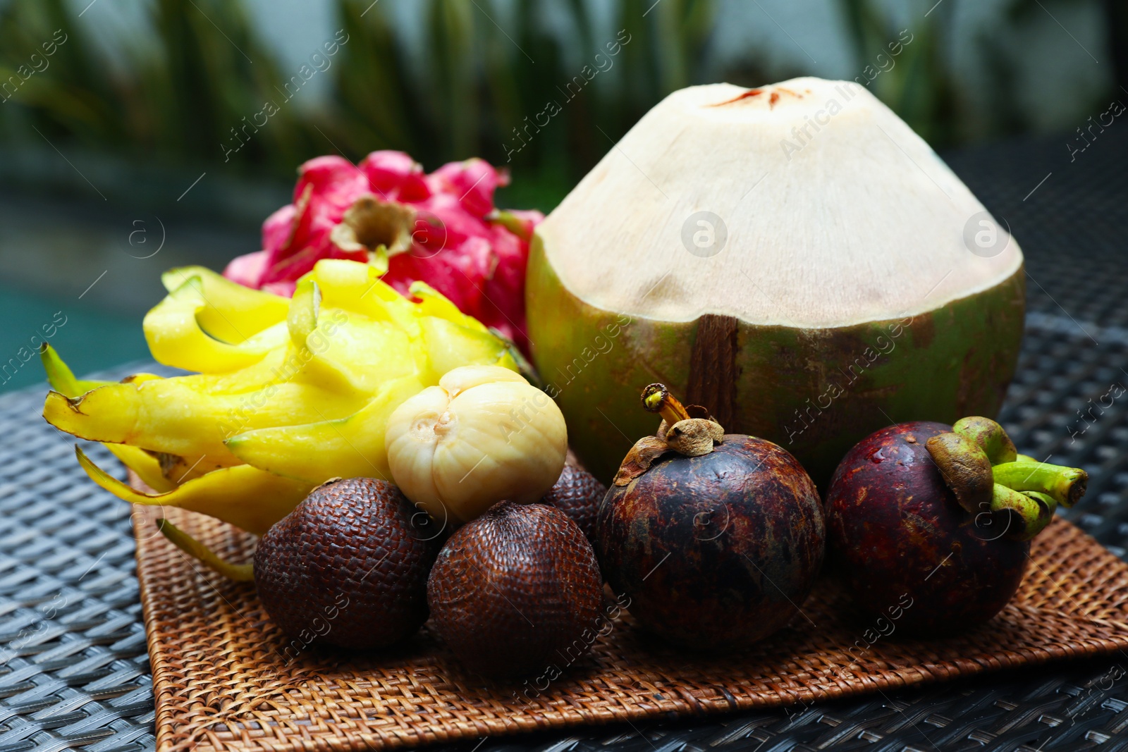 Different tropical fruits on wicker table, closeup Photo of Different tropical fruits on wicker table, closeup