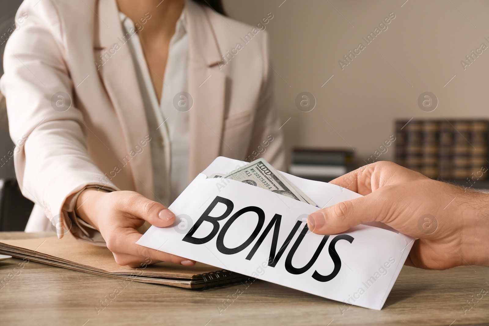Employee receiving envelope with bonus from boss at wooden table, closeup Image of Employee receiving envelope with bonus from boss at wooden table, closeup