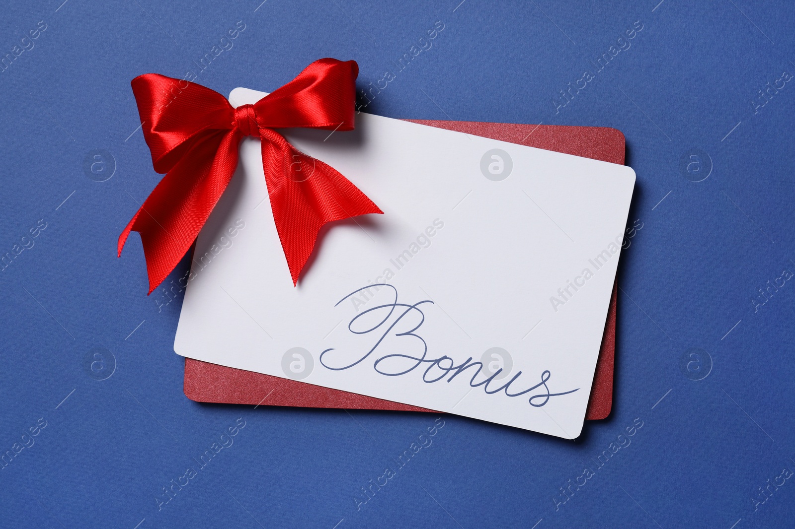 Bonus card with red bow on blue background, top view Image of Bonus card with red bow on blue background, top view