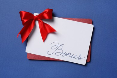 Image of Bonus card with red bow on blue background, top view