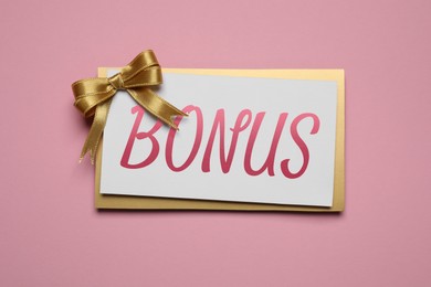 Image of Bonus card with golden bow on pink background, top view