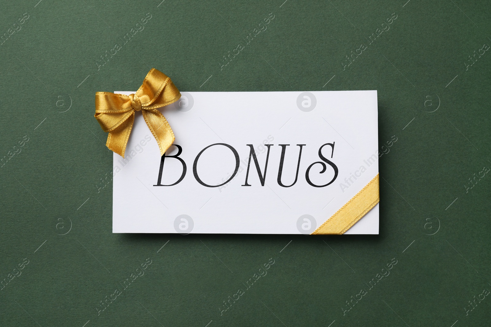 Bonus card with golden bow on green background, top view Image of Bonus card with golden bow on green background, top view