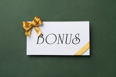 Image of Bonus card with golden bow on green background, top view