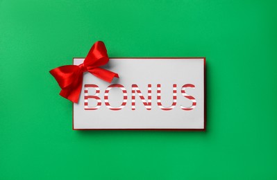 Image of Bonus card with red bow on green background, top view