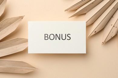 Image of Bonus card and decorative plants on beige background, flat lay