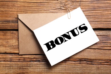 Image of Paper with word Bonus, and envelope on wooden table, top view