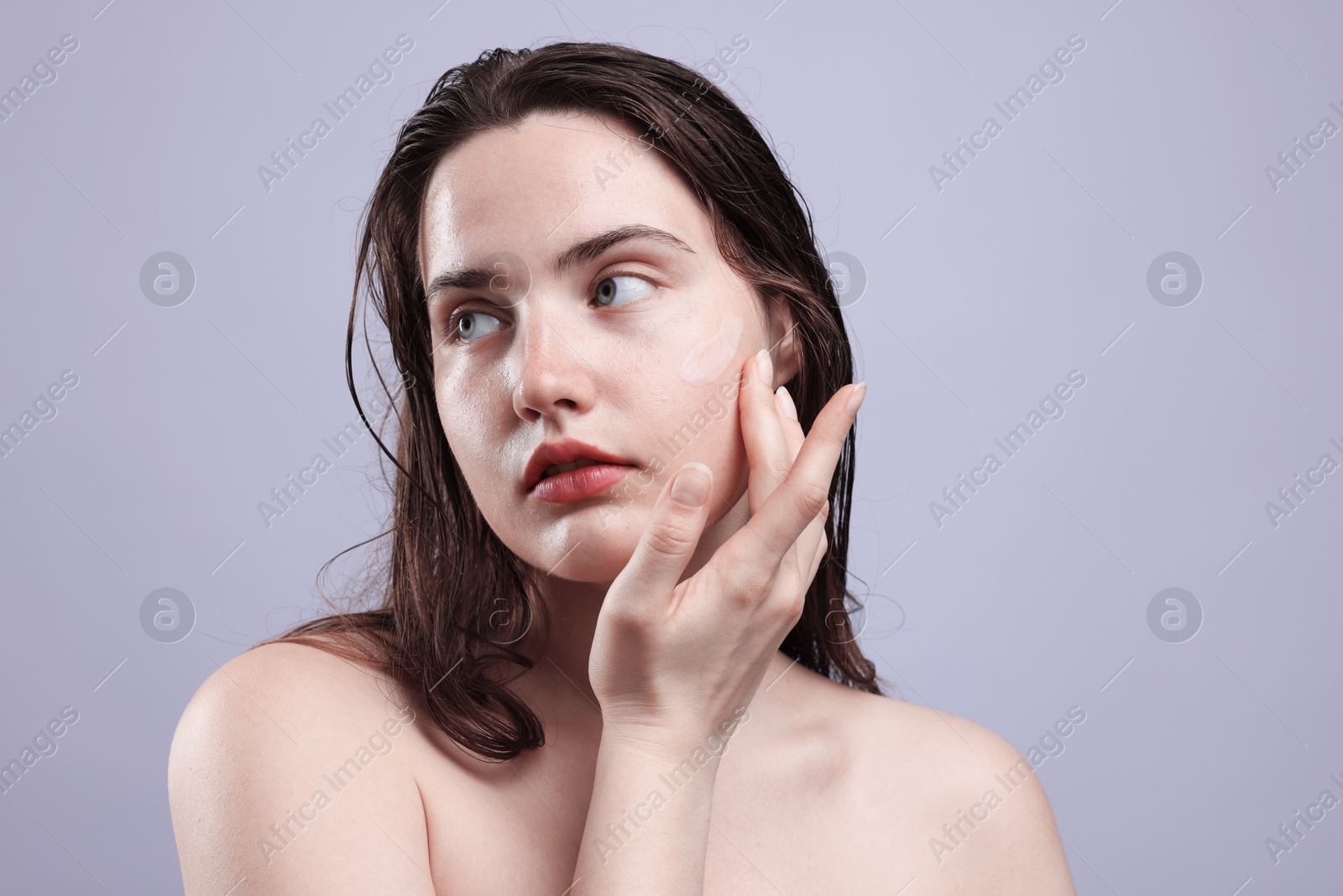 Beautiful woman with skincare product on her face against grey background, closeup Photo of Beautiful woman with skincare product on her face against grey background, closeup