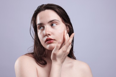 Photo of Beautiful woman with skincare product on her face against grey background, closeup