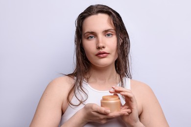 Photo of Portrait of beautiful woman with jar of skincare product on light grey background, closeup