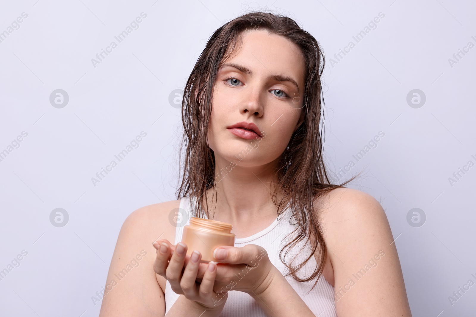 Portrait of beautiful woman with jar of skincare product on light grey background, closeup Photo of Portrait of beautiful woman with jar of skincare product on light grey background, closeup