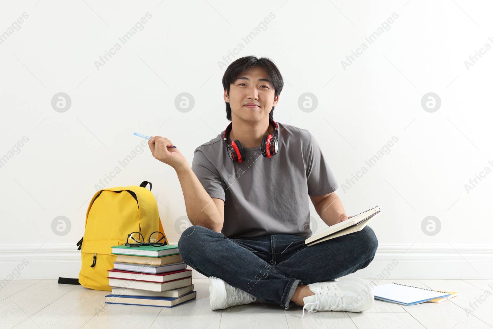 Photo of Student with notebook and pen studying on floor indoors