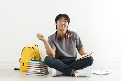 Photo of Student with notebook and pen studying on floor indoors