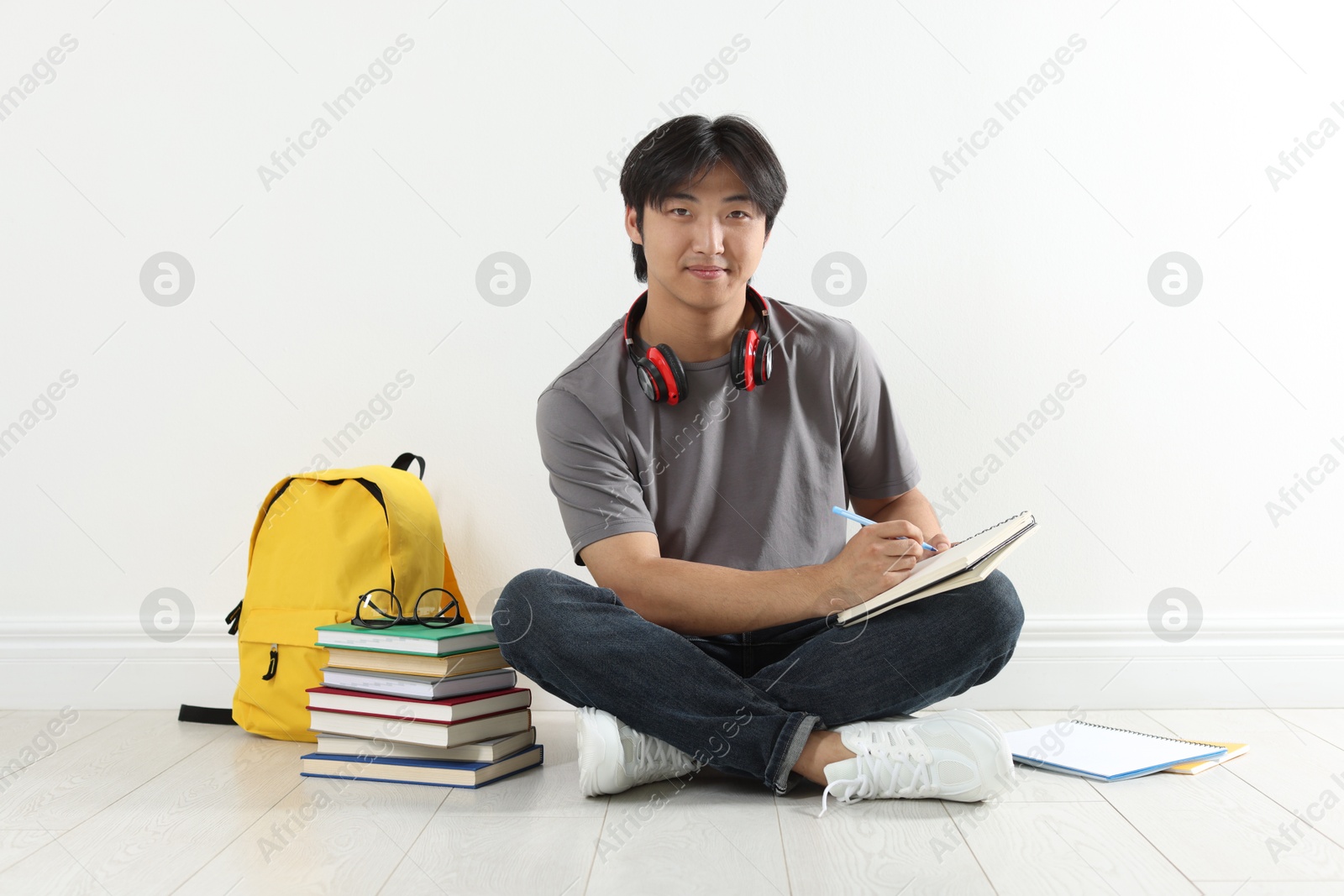 Student with notebook and pen studying on floor indoors Photo of Student with notebook and pen studying on floor indoors