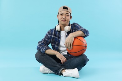 Photo of Student with headphones and basketball ball on light blue background