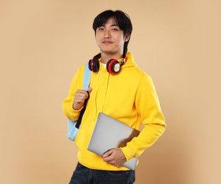 Photo of Student with laptop and backpack on beige background