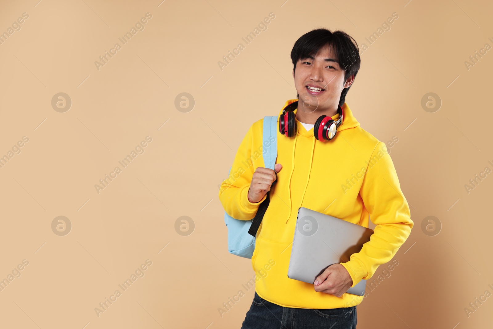 Student with laptop and backpack on beige background, space for text Photo of Student with laptop and backpack on beige background, space for text