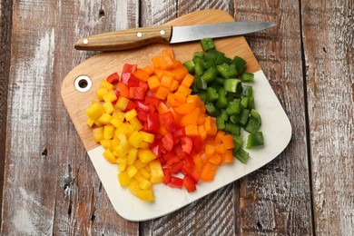 Photo of Cut colorful bell peppers on wooden table, top view