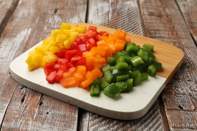 Photo of Cut colorful bell peppers on wooden table, closeup