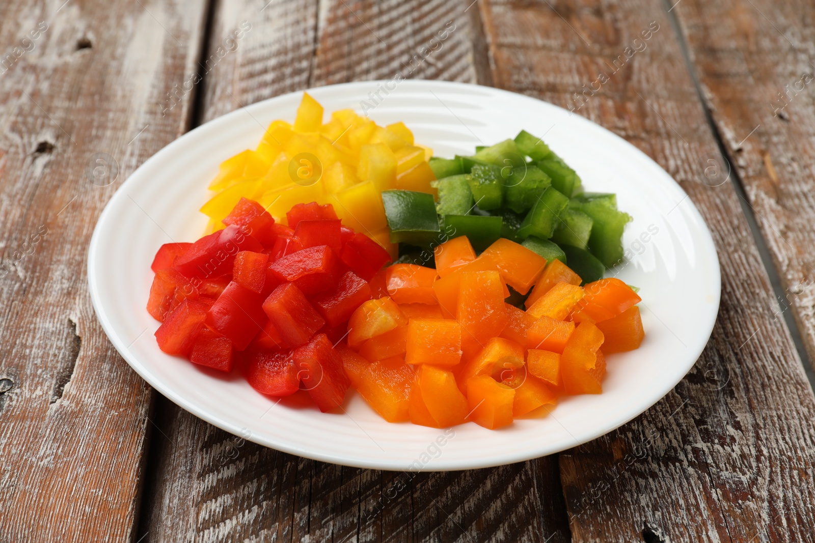 Cut colorful bell peppers on wooden table, closeup Photo of Cut colorful bell peppers on wooden table, closeup