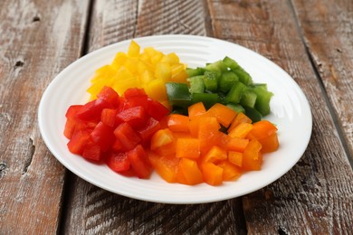Photo of Cut colorful bell peppers on wooden table, closeup