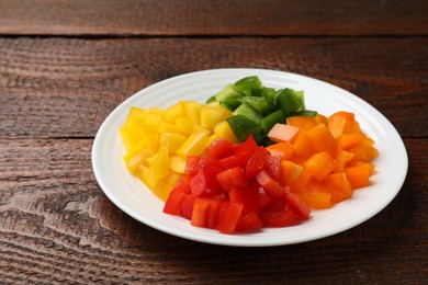 Photo of Cut colorful bell peppers on wooden table, closeup