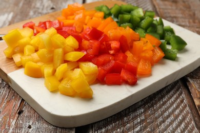 Photo of Cut colorful bell peppers on wooden table, closeup