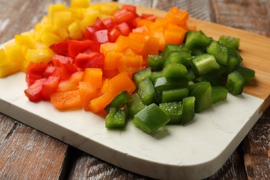 Photo of Cut colorful bell peppers on wooden table, closeup