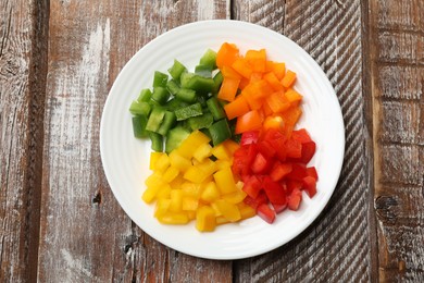 Photo of Cut colorful bell peppers on wooden table, top view