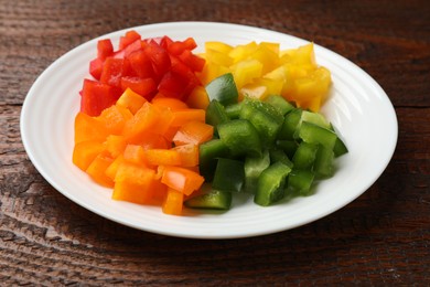 Photo of Cut colorful bell peppers on wooden table, closeup