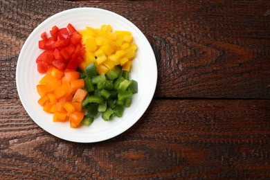 Photo of Cut colorful bell peppers on wooden table, top view. Space for text