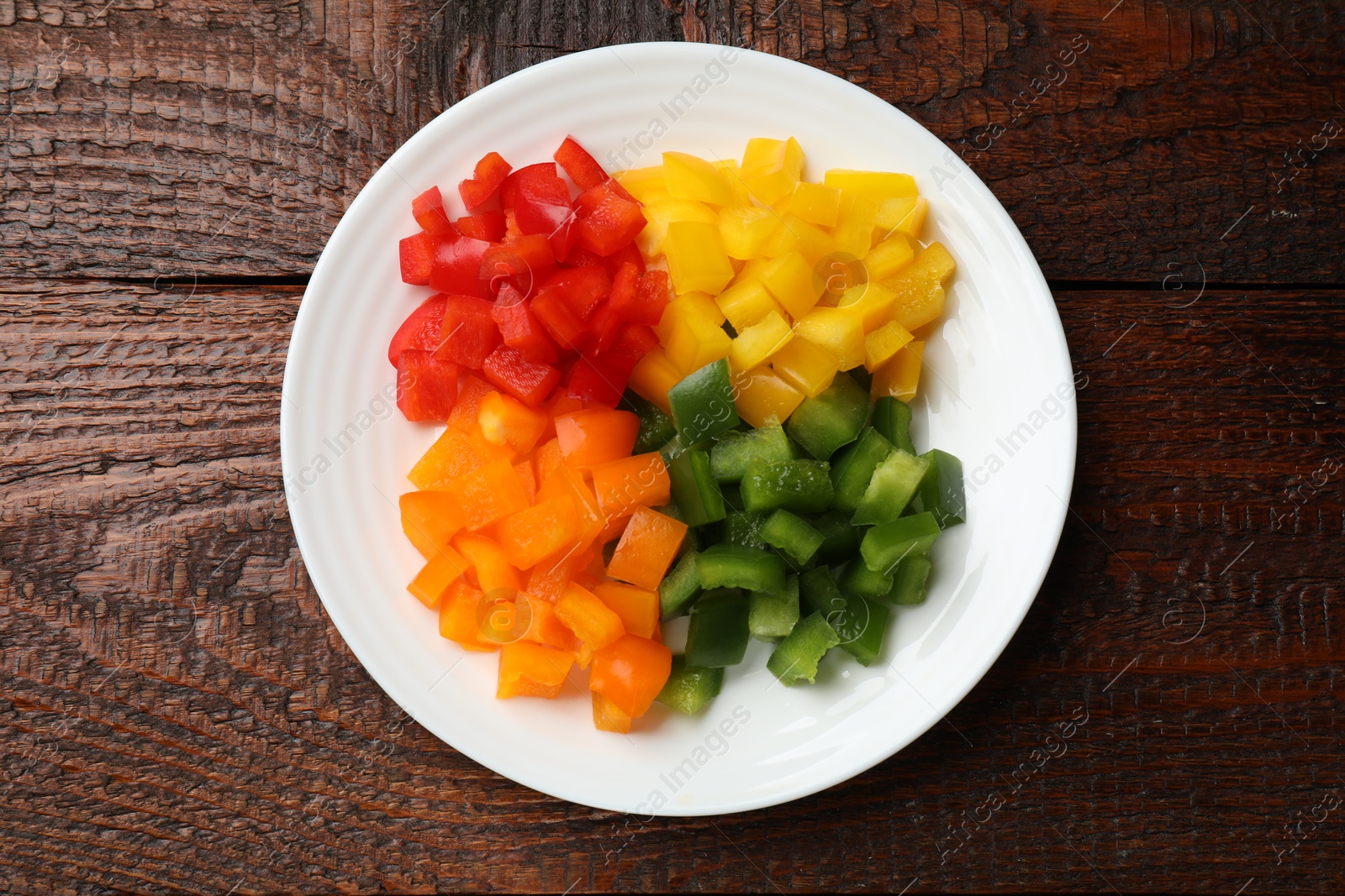 Cut colorful bell peppers on wooden table, top view Photo of Cut colorful bell peppers on wooden table, top view