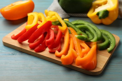 Photo of Cut colorful bell peppers on blue wooden table, closeup