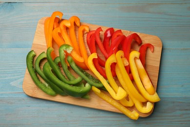 Photo of Cut colorful bell peppers on blue wooden table, top view