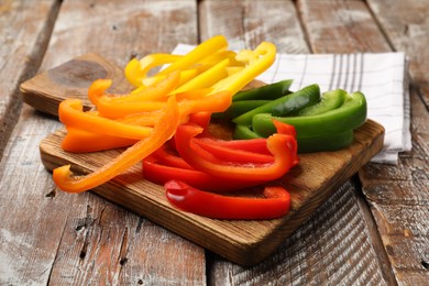 Photo of Cut colorful bell peppers on wooden table, closeup