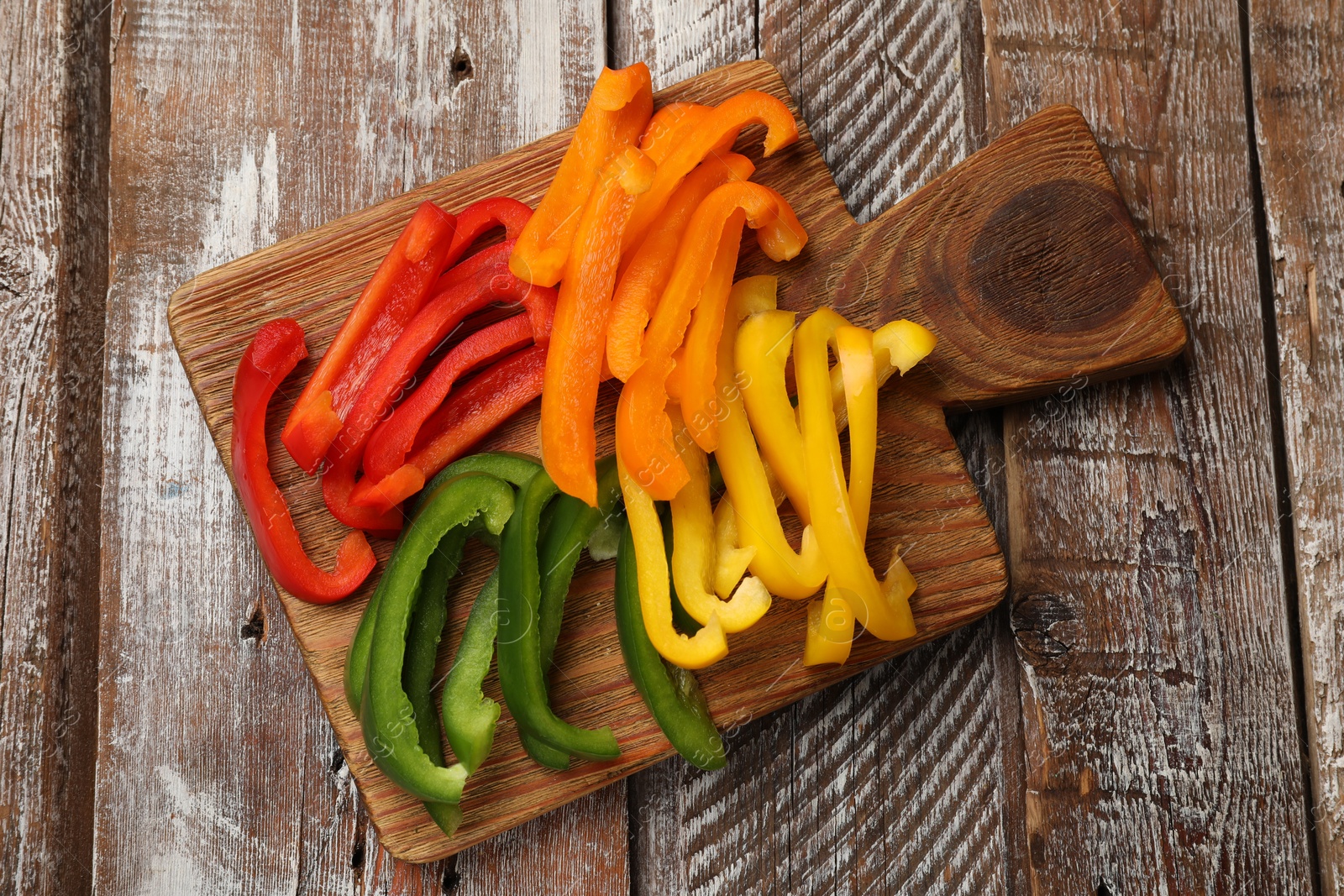 Cut colorful bell peppers on wooden table, top view Photo of Cut colorful bell peppers on wooden table, top view