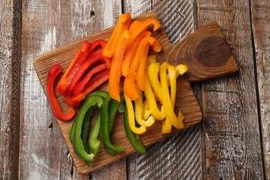 Photo of Cut colorful bell peppers on wooden table, top view