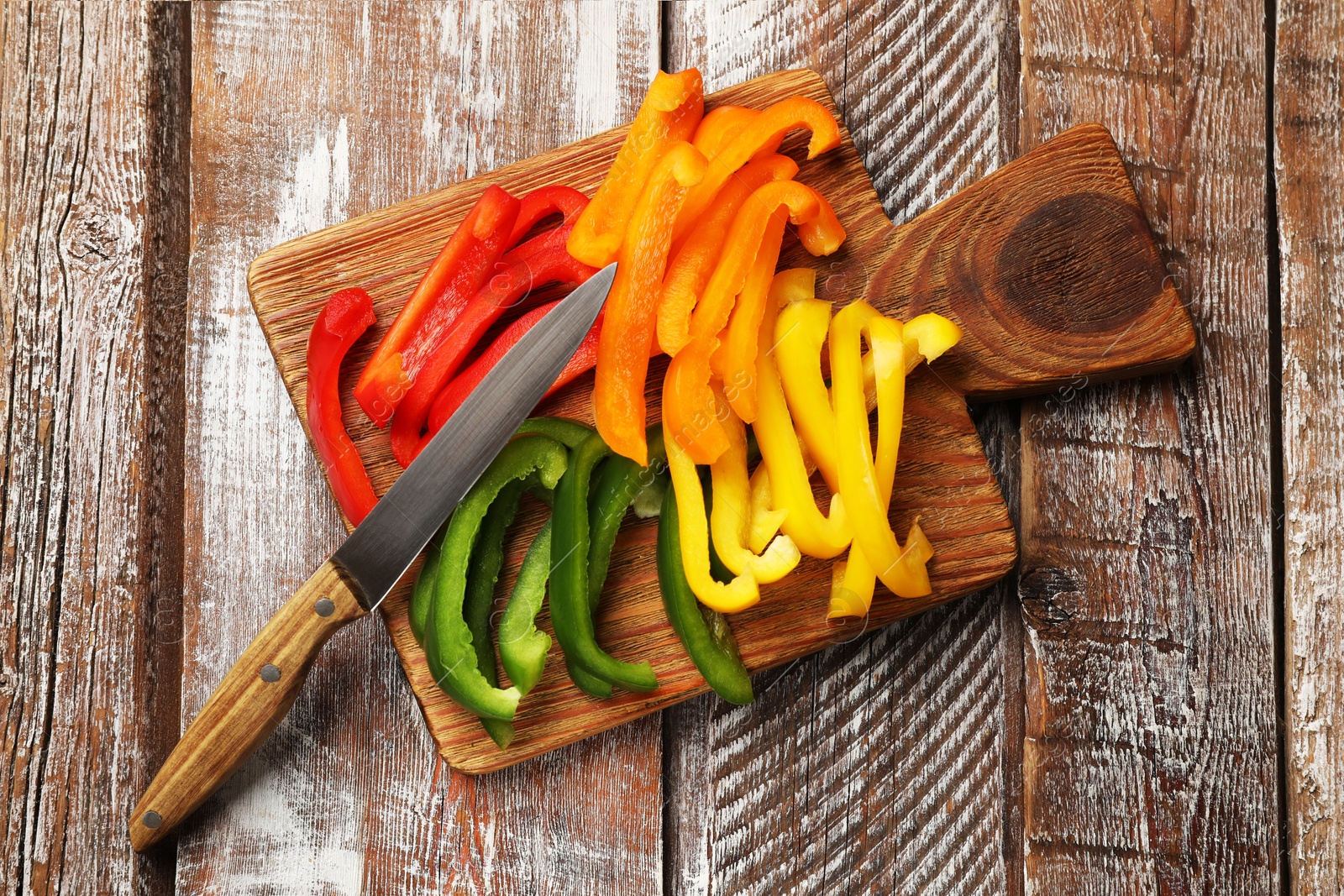 Cut colorful bell peppers on wooden table, top view Photo of Cut colorful bell peppers on wooden table, top view