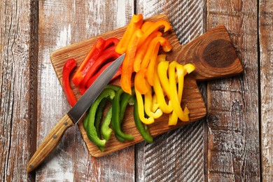 Photo of Cut colorful bell peppers on wooden table, top view