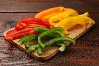Photo of Cut colorful bell peppers on wooden table, closeup