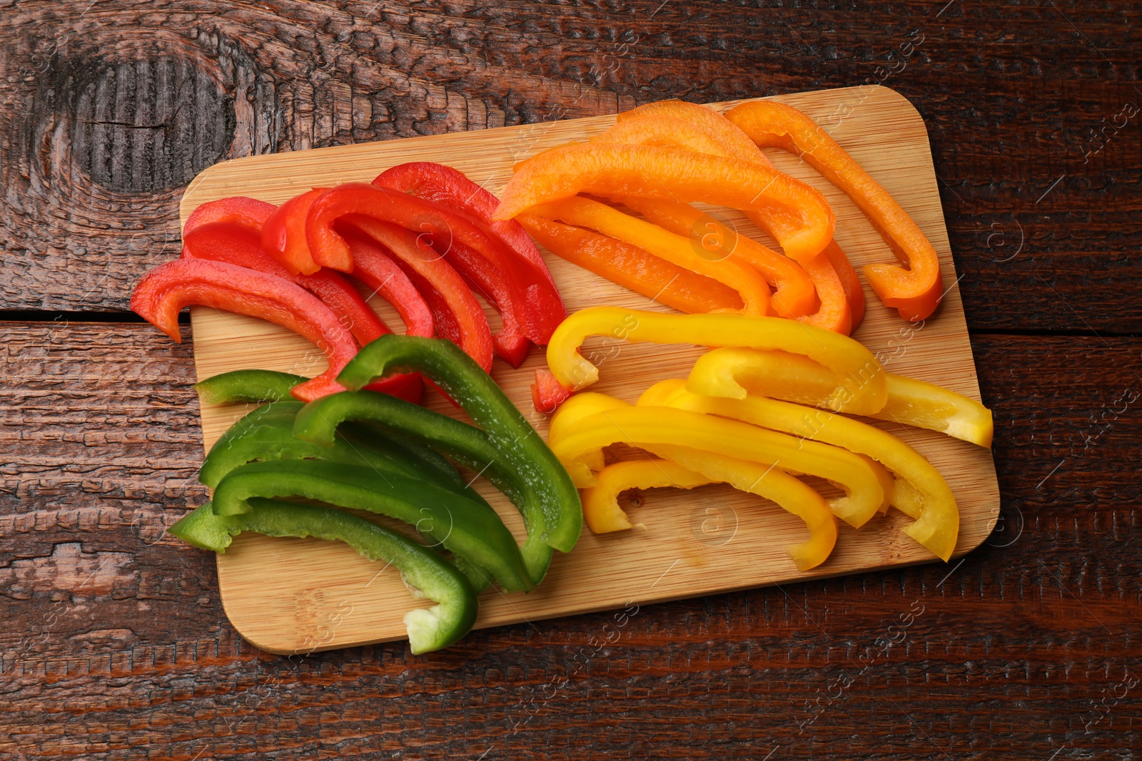 Cut colorful bell peppers on wooden table, top view Photo of Cut colorful bell peppers on wooden table, top view
