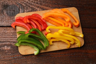 Photo of Cut colorful bell peppers on wooden table, top view