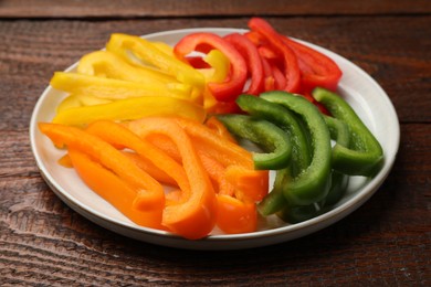 Photo of Cut colorful bell peppers on wooden table, closeup