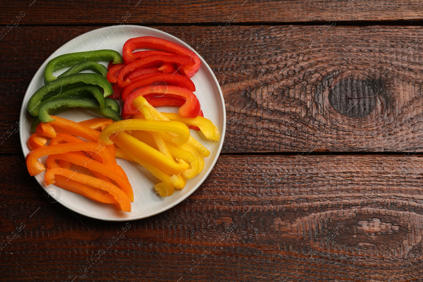 Cut colorful bell peppers on wooden table, top view. Space for text Photo of Cut colorful bell peppers on wooden table, top view. Space for text